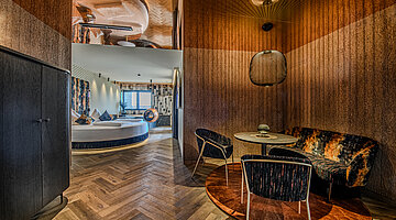 Living and Dining Area in the Private Cinema Suite Living and dining area in the Private Cinema Suite at Hotel Winzer with a cosy seating area, dining table and views towards the sleeping area