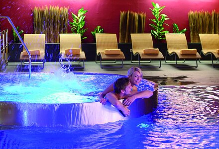 A woman and a man in the indoor pool at the Emotion SPA in the Wellnesshotel Winzer on Lake Attersee