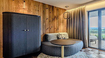 Living Area in the Kuschelnest Junior Suite Cosy living area in the Kuschelnest Junior Suite at Hotel Winzer with rounded seating, natural wood panelling and balcony access