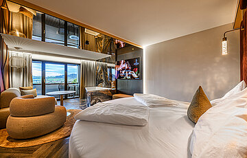 Schlafbereich der Juniorsuite Kuscheltraum im Hotel Winzer mit Doppelbett, gemütlicher Sitzecke, Badewanne und Balkon mit Ausblick