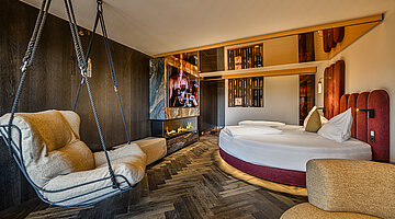 Schlafbereich mit Kamin Schlafbereich der Secret Love Suite im Hotel Winzer mit rundem Doppelbett, Hängesessel und modernem Kamin
