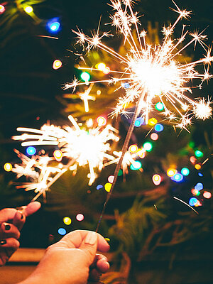 sparklers burning against a backdrop of blurred, colourful lights