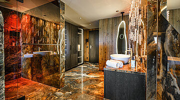 Open-Plan Bathroom in the Kuschelnest Junior Suite Luxurious open-plan bathroom in the Kuschelnest Junior Suite at Hotel Winzer with natural stone, rainfall shower and illuminated mirror