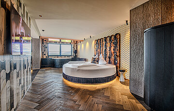 Wolke 7 im Hotel Winzer mit rundem Doppelbett, privatem Whirlpool und großzügigem Wohn- und Schlafbereich für zwei