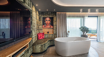 Schlafzimmer mit freistehender Badewanne in der Private Spa Villa im Hotel Winzer