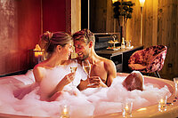 Pärchen im Whirlpool mit Sekt in der Kuschelsuite im Hotel Winzer