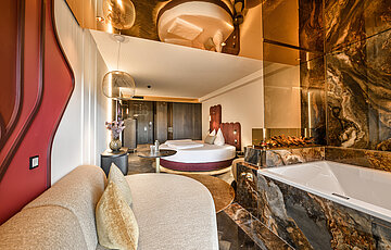 Gemütlicher Wohnbereich der Juniorsuite Kuscheltraum Deluxe im Hotel Winzer mit Sitzecke, Kamin, Balkon und Blick in die Landschaft