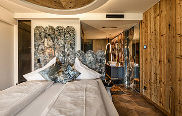 Stilvoller Schlafbereich der Juniorsuite Kuschelnest im Hotel Winzer mit Doppelbett, Naturholz und exklusivem Interior